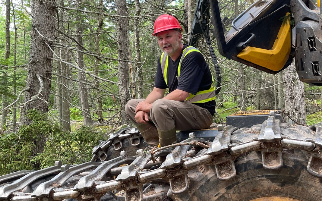 Man sitting on piece of forestry equipment in woods